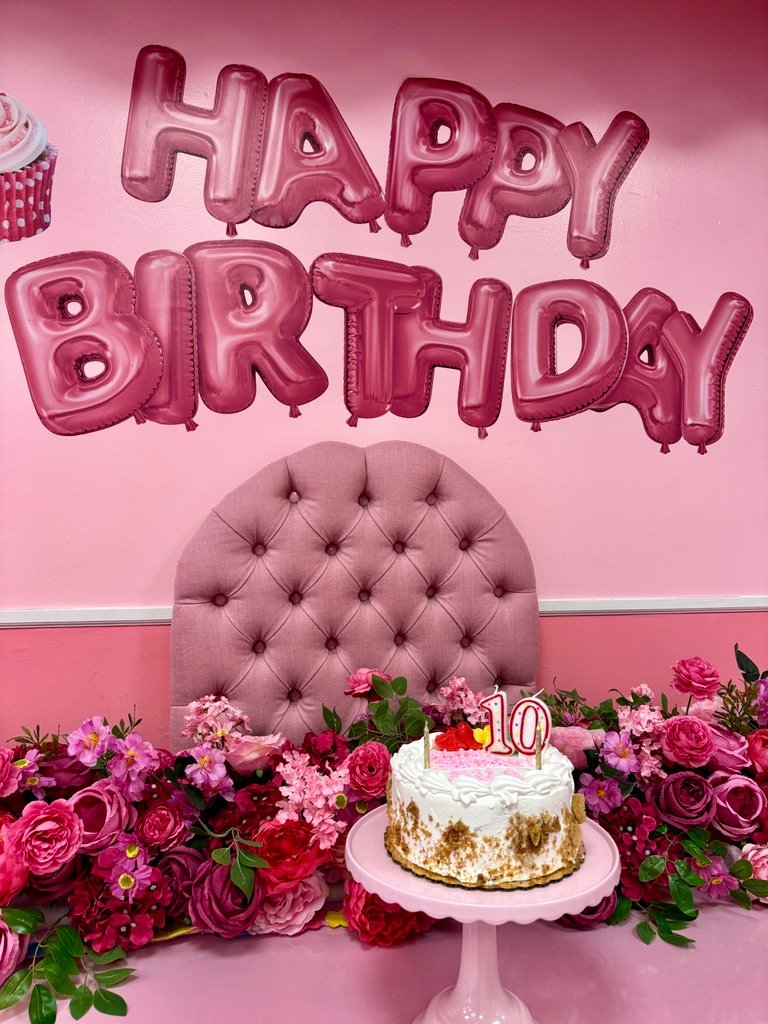 Happy Birthday setup with pink balloons and cake at Lollipop Spa